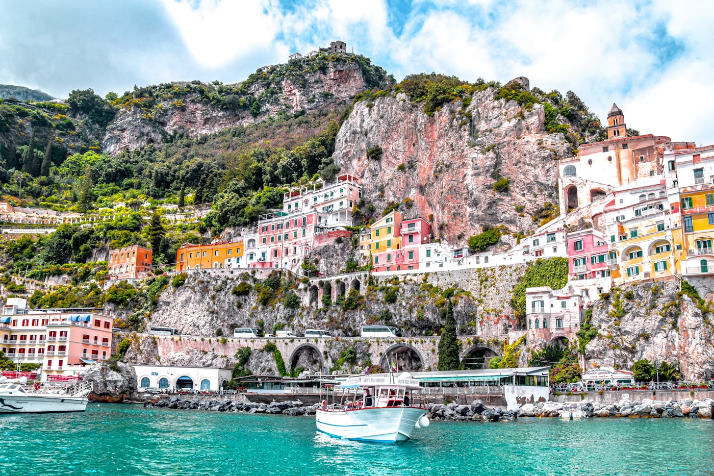 Colorful cliffside buildings and the coastal road tunneling through rock at Amalfi, Italy